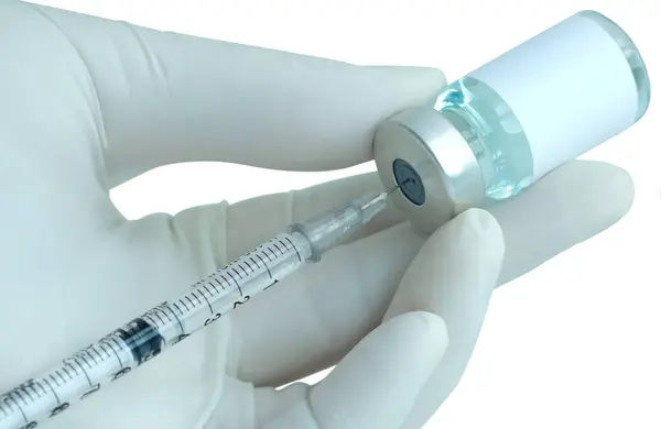 Doktorun elinde hastanede bir şırınga ve mavi bir aşı şişesi var. Sağlık ve tıbbi kavramlar