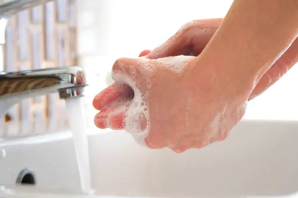 美女的手在洗脸盆用泡沫洗手 洗净皮肤 让水从手上流过 健康和美的概念 免版税图库照片