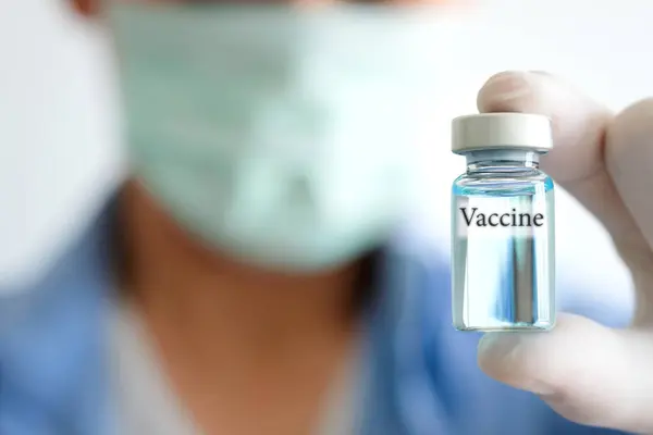 医生的手在医院里拿着一个注射器和一个蓝色疫苗瓶 健康和医疗概念 免版税图库图片