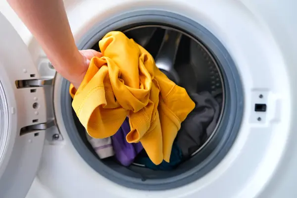 女人的手拿起衣服洗衣机 清洁健康的概念 免版税图库照片