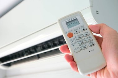 Adamın eli uzaktan kumanda ile açılıyor klima yatak odasında 25 santigrat dereceye kadar soğutuluyor. Sağlık kavramları ve enerji tasarrufları