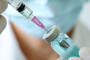 Doktorun elinde hastanede bir şırınga ve mavi bir aşı şişesi var. Sağlık ve tıbbi kavramlar