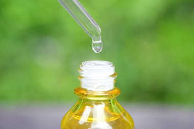 Yüzün serum kolajen nemlendiricisini açık sarı şişe yumuşak ışık arka planına döküyorum. Koruyucu cilt bakımı yüz özü yağı, C vitamini güzellik ve kaplıca konsepti.