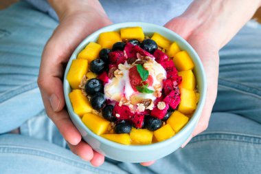 Elinde bir kase taze çilek ve yaban mersinli yoğurt tutan bir kadın. Sağlıklı beslenme ve kilo kontrolü kavramı.