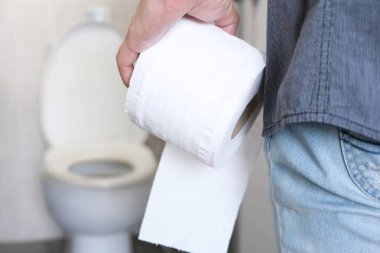 Adamın eli, bir rulo tuvalet kağıdı tutuyor. Tuvalet arka planına gidiyor.