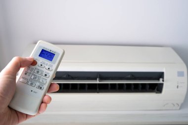 Adamın eli uzaktan kumanda ile açılıyor klima yatak odasında 25 santigrat dereceye kadar soğutuluyor. Sağlık kavramları ve enerji tasarrufları