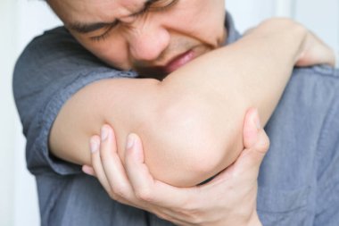 Kadın dirseklerini tutmak için ellerini kullanıyor ve dirseklerinde ağrı var. Acı verici Sağlık ve Tıbbi Konseptler