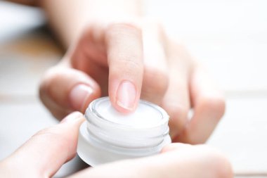 Nemlendirici krem ve serum tutan kadının eli. Yüz kremi sürüyor, cilt bakımı için yağ, losyon ve vücut kremi, yakın görüş ve bulanık arka plan. Güzellik ve Sağlık Konsepti.