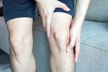 Diz ağrısı. Adam parkta duruyor. Eli dizinden sıkıştı. Acıyı dindirmek için ayaklarının ağrıması ve kaslarının yorulması. sağlık kavramları.