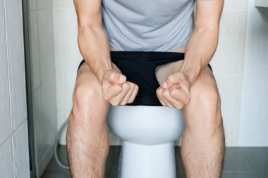 Tuvalette oturan adam. Banyoda, evi kabızlık, ishal, gıda zehirlenmesi, sağlık ve tıbbi kavramlardan memnun değil..