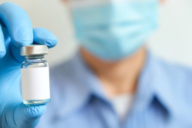 Doktorun elinde hastanede bir şırınga ve mavi bir aşı şişesi var. Sağlık ve tıbbi kavramlar.