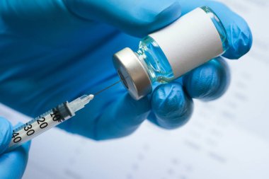 Doktorun elinde hastanede bir şırınga ve mavi bir aşı şişesi var. Sağlık ve tıbbi kavramlar.