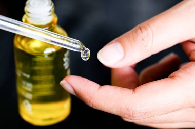 hands of a beautiful woman Dropping serum collagen moisturizer of face into clear gold bottle soft light background. Protector skin Treatment facial essence oil, Vitamin C. Beauty and spa Concept