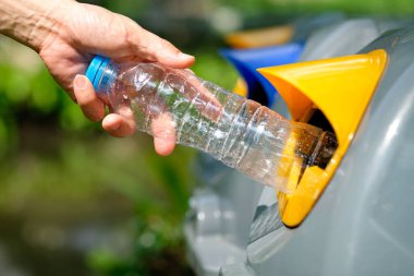 Lütfen plastik şişeyi depoya atın. Bir adam çöp tenekesine çöp atar gibi çöp atmak için çöpleri ayırır. ,