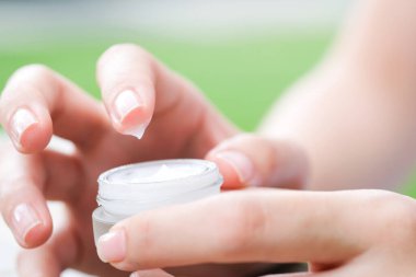 Nemlendirici krem ve serum tutan kadının eli. Yüz kremi sürüyor, cilt bakımı için yağ, losyon ve vücut kremi, yakın görüş ve bulanık arka plan. Güzellik ve Sağlık Konsepti.