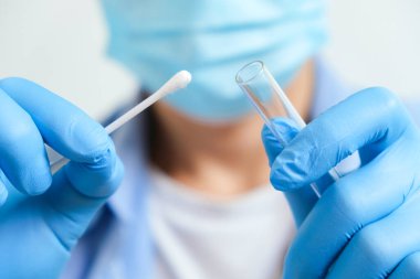Doktor COVID-19 numune koleksiyonu yapıyor, mavi eldiven ve PPE koruyucu maske takıyor ve OP NP ve Coronavirus 'u test etmek için test tüpü taşıyor..