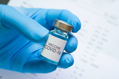 Doktorun elinde hastanede bir şırınga ve mavi bir aşı şişesi var. Sağlık ve tıbbi kavramlar.