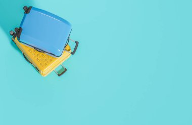 Açık mavi arka planda düz sarı ve mavi bavul vardı. Yaz seyahati konsepti, 3D model ve illüstrasyon.