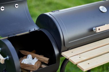 New smoker barbecue grill. Stack wood and light it properly. Closeup.