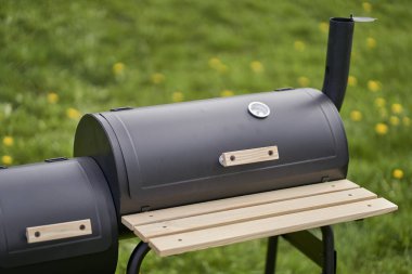 New smoker barbecue grill. Equipment for cooking and smoking. Closed burning and smoking chamber.