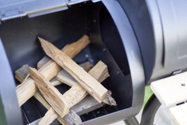 New smoker barbecue grill. Stack wood and light it properly. Closeup.