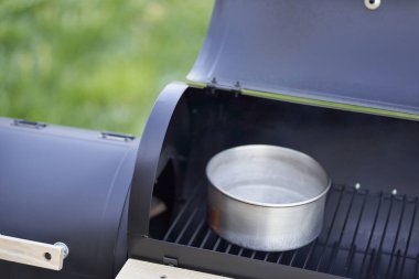 New smoker barbecue grill. Pot with water in open chamber, prevents drying out of grilled food.