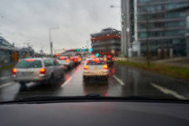 Raindrops on the windshield. Rush hour traffic in the city. Cockpit view.