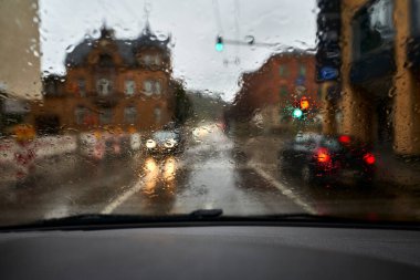 Driving a car in the rain. Drops on the windshield. City.