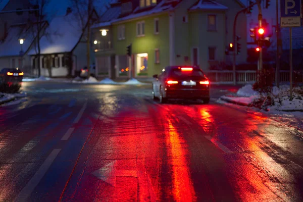 Buzlu ve karlı bir yol (Blitzeis, Glatteis). Sabah yol ayrımında tehlike var. Araç kırmızı ışıkta, derinlik bulanıklığında. Almanya, Nurtingen.