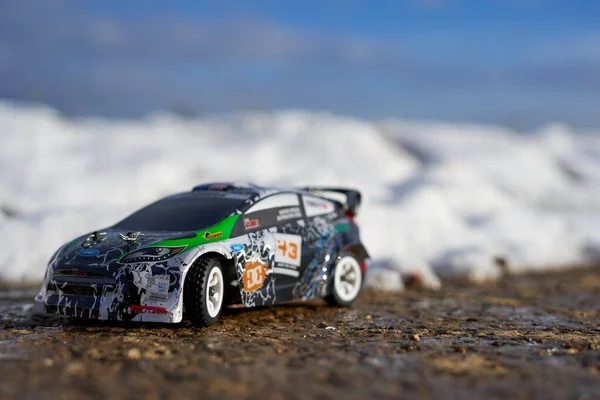 Kongen, Almanya - 19 Ocak 2023: Çocuklar için hızlı radyo kontrol aracı. WLtoy 'dan Mini RC yarış arabası. Dışarıda karda, taşlı bir yolda..