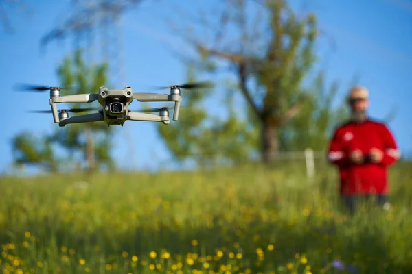 stock image Nurtingen, Germany - May 29, 2021: Drone dji air 2s. Modern multicopter over wildflower field. Pilot with red sweater blurred in background.