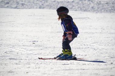 Feldberg, Almanya - 08 Şubat 2023: Kayak başlangıcı karda yokuş aşağı kayak yapıyor. Küçük kız kayak okulunda kış sporları öğreniyor. Kayak kursu.