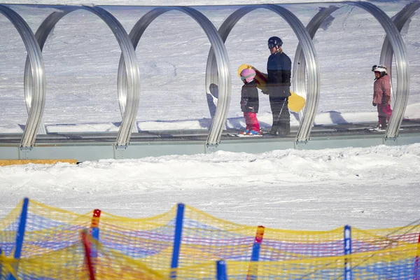 Feldberg, Almanya - 08 Şubat 2023: Yeni başlayanlar için asansörde kayak binicileri. Kış sporlarını öğrenmek için konveyör bantlı tüp. Babası ve kızı kayak kursunda..