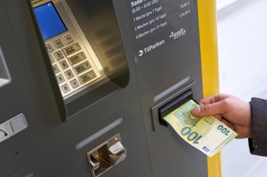 Tubingen, Almanya - 31 Aralık 2023: makinenin ücretini öde. Park etmek pahalıdır. El, banknotu makineye sokuyor..
