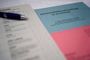 Mavi kalemli bir Alman oy pusulası. (Almanca kelime Briefwahl: posta oylaması). Demokrasilerde posta oylamasını sembolize eden zarf.
