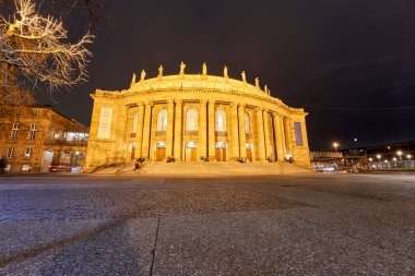 Stuttgart, Almanya - 26 Aralık 2023: Büyük sütunları ve klasik mimarisi ile aydınlatılmış Stuttgart Devlet Tiyatrosu 'nun gece görüşü. Almanya.