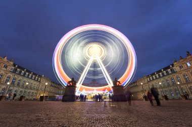 Stuttgart, Almanya - 26 Aralık - 26, 2023: Stuttgart Şatosu Meydanı alacakaranlıkta, parlak bir dönme dolaba sahip, neşeli bir atmosfer yaratıyor. Önemli noktalar (Glanzlichter). Almanya, Stuttgart.