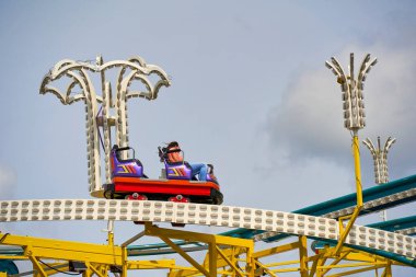 Stuttgart, Almanya - Mayıs - 06, 2023: Parçalı bulutlu bir gökyüzüne karşı düzenlenen Stuttgart bahar festivalinde iki biniciyle renkli lunapark treni.