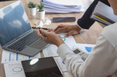 Team of business use calculators and graph analysis computer laptop tablets to plan marketing strategies and make profitable investments for the company.
