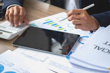 İş adamı, pazarlama stratejileri planlamak ve şirket için kârlı yatırımlar yapmak için hesap makineleri ve grafik analizi bilgisayar tabletleri kullanır.