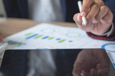 İş adamı, pazarlama stratejileri planlamak ve şirket için kârlı yatırımlar yapmak için hesap makineleri ve grafik analizi bilgisayar tabletleri kullanır.