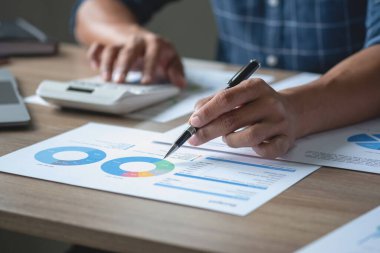 İş adamı, pazarlama stratejileri planlamak ve şirket için kârlı yatırımlar yapmak için hesap makineleri ve grafik analizi bilgisayar tabletleri kullanır.