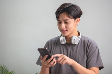 Rahatla, stres at, tatil yap, mutlu ol, Asyalı kadın evde rahatla ve akıllı telefondan mutlu bir şekilde müzik dinle..