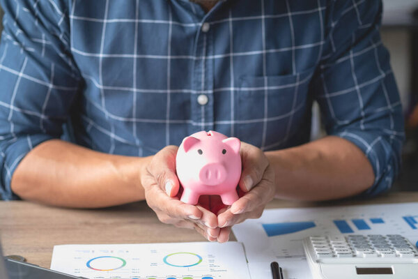 man holding a coin to drop a piggy bank For saving money for the future of the family, saving ideas.
