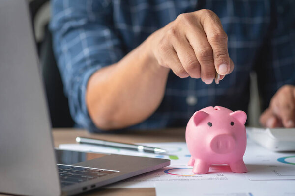 man holding a coin to drop a piggy bank For saving money for the future of the family, saving ideas.