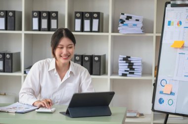Portrait of a female accountant using a calculator and laptop to calculate balance using graphs for customers.