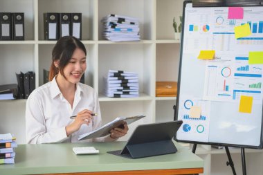 Portrait of a female accountant using a calculator and laptop to calculate balance using graphs for customers.