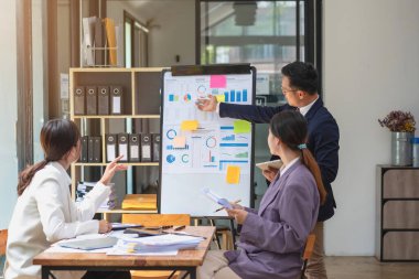 Takım işi üç gülümseyen ve mutlu Asyalı erkek ve kadın takımı tablet ve dizüstü bilgisayarları kullanarak şirket içindeki bir şirket çizelgesinde istatistikler oluşturuyorlar. Meslektaşlar konsepti.