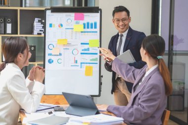 Takım işi üç gülümseyen ve mutlu Asyalı erkek ve kadın takımı tablet ve dizüstü bilgisayarları kullanarak şirket içindeki bir şirket çizelgesinde istatistikler oluşturuyorlar. Meslektaşlar konsepti.