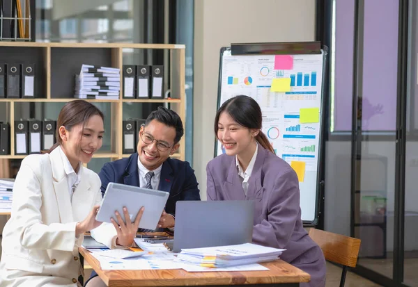 Asian business team consists of marketing staff. accountant and financial officer Help each other analyze company profits using tablets. calculator Laptop computers, graph paper, and corporate pens.